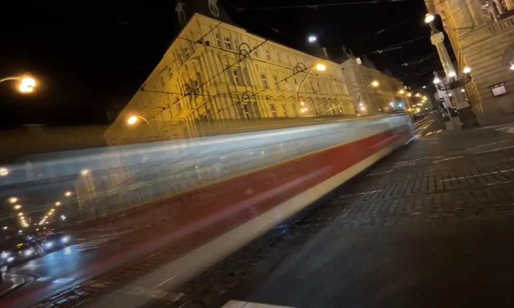 DrupalCon Prague 2022, showing a picture of a tram crossing the city at night.