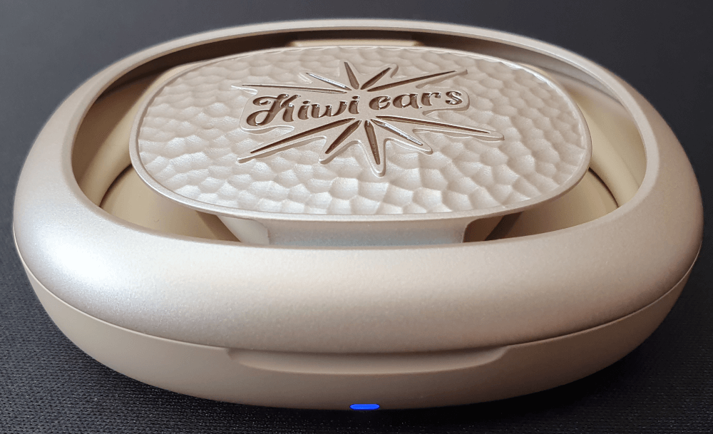 An outside shot of the Kiwi Ears Spark earphones case. The case is closed. There is a blue LED light on the front of the case.