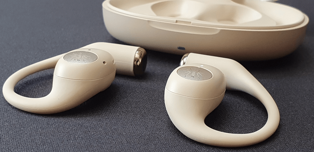 The Kiwi Ears Spark earphones, outside of the case and sat on a black fabric tabletop.