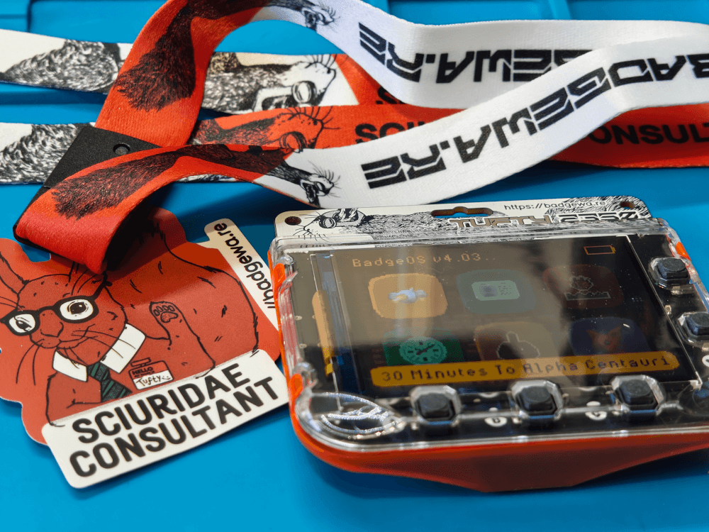 The Tufty2350 badge. Fresh out of the box next to the lanyard and a sciuridae consultant sticker.