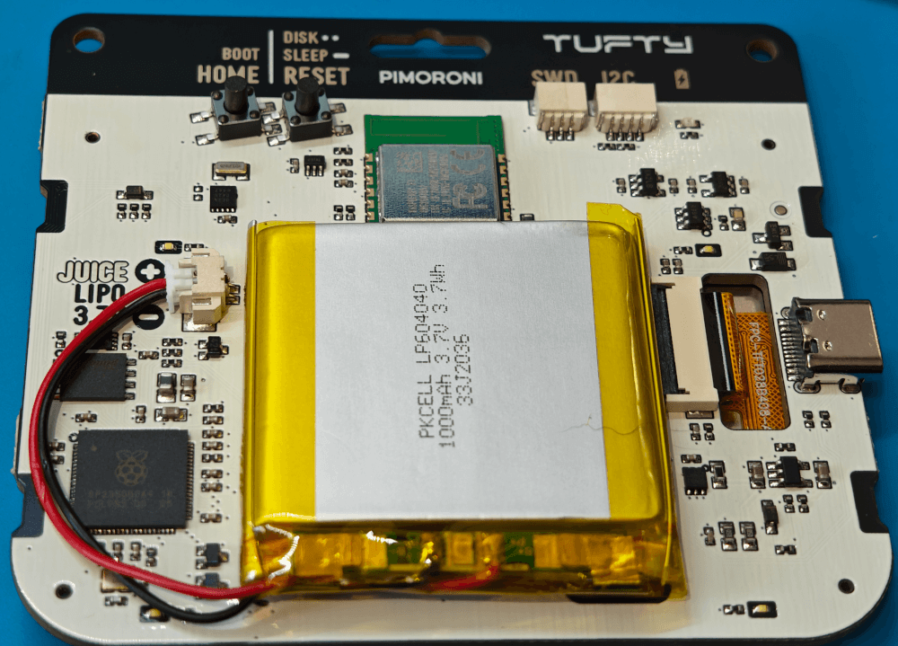 The inside back of the Tufty2350 badge. Showing the circuit board and the components.